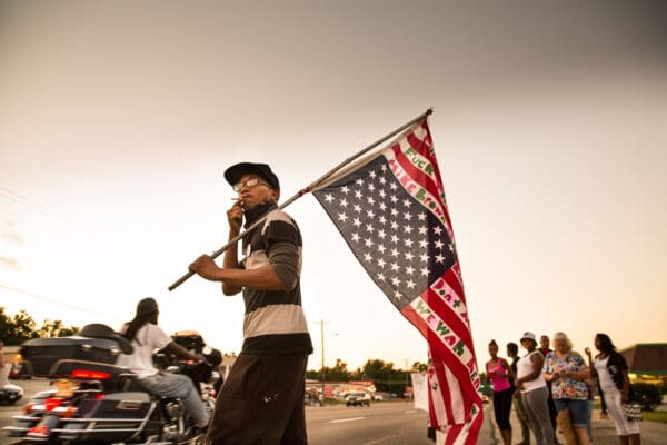 Lisa Johnston | lisajohnston@archstl.org | @aeternusphoto A young man crossed W. Florissant Ave. as protesters gathered for another night of demonstrations in Ferguson. After a state of emergency was declared in Ferguson, protesters taunted police with harsh language and accusations along W. Florissant Avenue. Posturing from one side of the street to the other and shouting their dislike of the police, the protesters threw bottles which caused the police to bring out body shields and pepper spray.  Monday’s demonstrations — dubbed “Moral Monday” —   included civil disobedience protesters who blocked the Thomas F. Eagleton U.S. Courthouse and other protesters who shut down a section of a major highway during rush hour commute.  Arrests during the day, including those made during demonstrations in downtown St. Louis, nearly 150 persons.